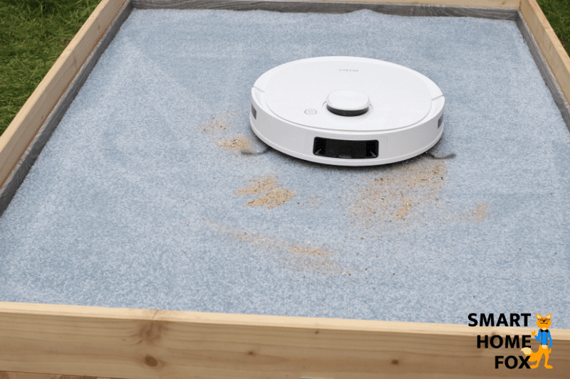Ecovacs Deebot T9 reinigt Sand auf einem hochflorigen Teppich